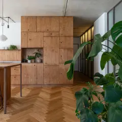 Nowoczesne wnętrze z drewnianymi meblami, roślinami i jodełkową podłogą.
